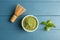 Matcha tea in bowl, whisk and green leaves on wooden table