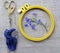 Materials for embroidery: scissors, canvas, thread and embroidery frame. Small blue lobelia flowers