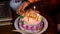 maternal grandmother lighting maternal grandmother candles with birthday cake at coffee table