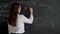 Math teacher writing equation or function on blackboard in school classroom. Student doing exercise on chalkboard in