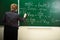 Math teacher writing formula on the blackboard