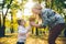 mather with little toddle daughter playing in autumn city public park