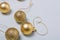 Matt and shiny golden bulbs on strings on light wooden background, plastic decorative Christmas baubles, closeup shot