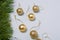 Matt and shiny golden bulbs on strings on light wooden background, plastic decorative Christmas baubles, pine tree branches border