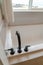 Matte black faucet and handles on a glossy clean white built in bathtub