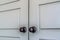 Matte black round door knobs of a double door with paneling inside a home
