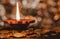 Matte effect. A terracotta lamp lit up with a straight and erect flame and round bokeh in the background, with coins around