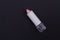 Matte pink lipstick without a cap on blackbackground.