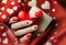Matte red nails with small red heart on beige colour nail on the red fabric background. Saint Valentine\\\'s nail design