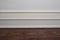 Matte wall, white baseboard and tiles immitating hardwood flooring