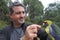 Mature adult man feeding feeding Green Rosella Bird