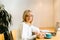 Mature adult woman sitting in cafe with coffee mug and working online on laptop. Businesswoman in eyeglasses typing on