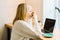 Mature adult woman sitting in cafe, drinking coffee mug and working online on laptop. Businesswoman in eyeglasses typing