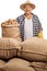 Mature agricultural worker posing with sacks with potatoes