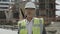 Mature architect in helmet standing on construction site