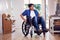 Mature Asian Man In Wheelchair Pushing Himself Along Hallway At Home