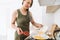 Mature asian woman cooking scramble eggs in kitchen