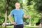 Mature athlete with headphones holding a hulahoop in park