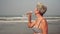 Mature attractive woman drinks water from a bottle on the beach