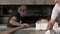 Mature baker taking out fresh baked bread from the industrial oven.