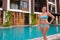 Mature beautiful Scandinavian tourist woman in bikini standing next to swimming pool