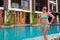 Mature beautiful Scandinavian tourist woman in bikini standing next to swimming pool