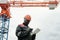 Mature black man in gloves, workwear and hardhat scrolling in tablet