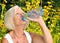 Mature, blonde woman drinking water.