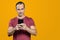 Mature Brazilian man holding smartphone at chest height and looking at camera. Orange background