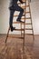 Mature businessman climbing wooden ladder in office