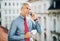 Mature businessman with smartphone standing on a terrace in city, making a phone call.