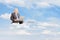 Mature businessman in suit flying on clouds with laptop outside