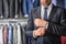 Mature businessman in suit with wristwatch in menswear store