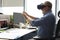 Mature businessman wearing a VR headset while sitting in modern office. Change the way you see and experience the world