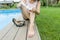 Mature businesswoman after a working day sits near the home pool. She took off her shoes and smeared her feet with soothing foot c