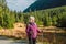 Mature caucasian blonde woman on vacation, having a hike in autumn mountains with backpack and hiking poles, enjoying