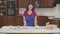 Mature caucasian brunette woman putting two plates on the table. One plate is empty, another one filled with flour