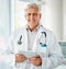 Mature caucasian male expert doctor smiling while using a digital tablet working at a hospital alone. One senior man