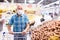 Mature caucasian man in mask with covid protection choosing potatoes in vegetable section of supermarke