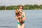 Mature caucasian woman plays ball in water with dog of Dachshund breed. Summertime theme with pet swim in river. Hot weather in