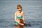 Mature caucasian woman plays ball in water with dog of Dachshund breed. Summertime theme with pet swim in river. Hot weather in