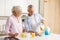 Mature cheerful loving couple family drinking juice eating corn flakes