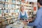 Mature cheerful woman standing among bookshelves