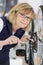 Mature cheerful woman tightening bicycle wheel screws in garage