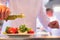 Mature chef using pouring oil on salad in plate at restaurant