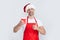 mature christmas man in red santa hat and apron hold coffee cup. thumb up