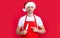 mature christmas man in red santa hat and apron point finger on kitchen knife