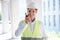 Mature constructor in professional equipment talking on walkie-talkie