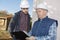 Mature contractor checking clipboard while talking to co-worker