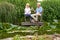 Mature Couple Celebrating With Champagne Sitting On Chairs On Wooden Jetty By Lake